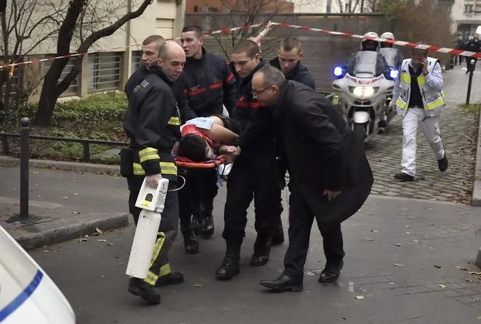 First responders evacuate a wounded victim on a stretcher from the scene of the Charlie Hebdo shooting in Paris.