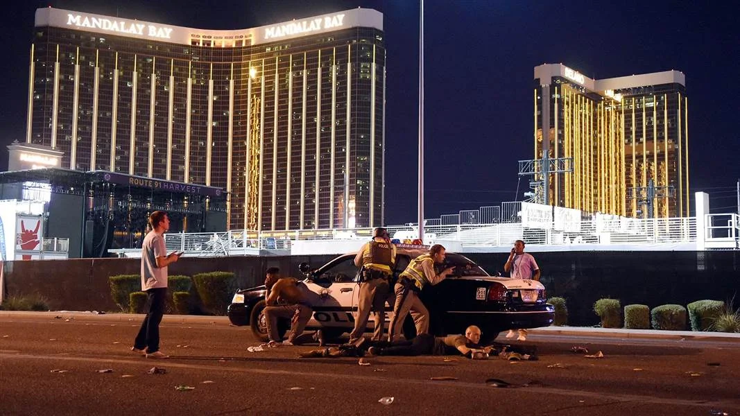 Police officers shelter behind a squad car near the Route 91 Harvest festival grounds during the October 1, 2017 mass shooting from the Mandalay Bay hotel.