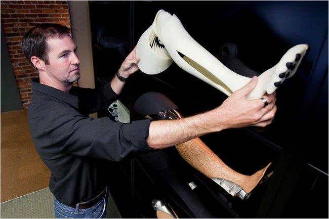 A designer inspects a 3D-printed prosthetic or fashion piece, showcasing the technology's use in custom manufacturing.