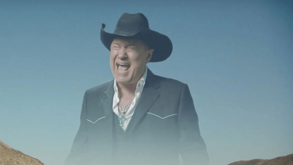 Jimmy Barnes' famous scream floating in the sky from the 'Big Enough' music video, the origin of the viral Screaming Cowboy meme.