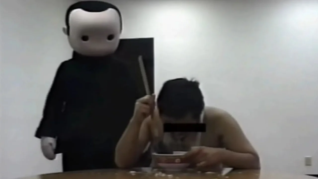 The original 'Blank Room Soup' video still, showing the crying man being fed by a blank-faced costumed figure.