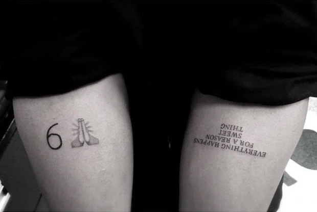Thigh tattoos combining the praying hands emoji frequently associated with the '#blessed' hashtag alongside an inspirational quote.