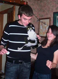 Two people holding cat as social gathering focal point.