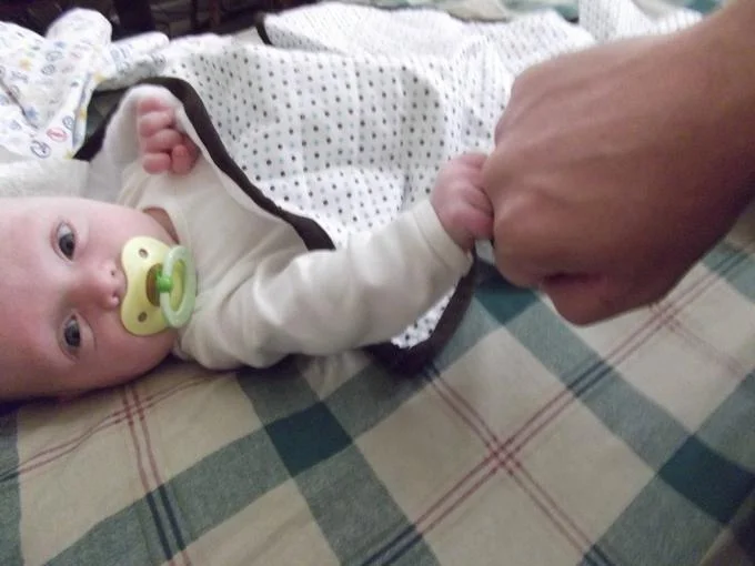A baby offers their first bro-fist to an adult, a wholesome variation of the meme.