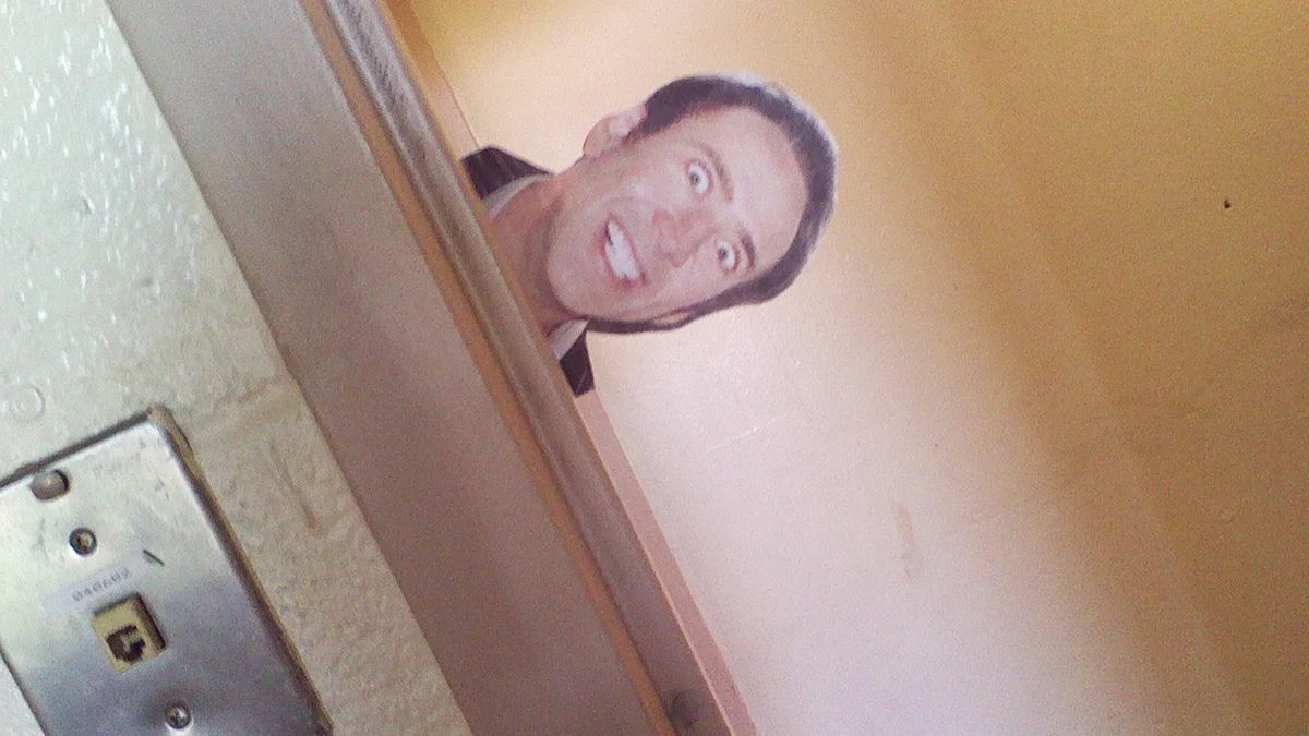 A classic 'caging' prank: a cutout of Nicolas Cage's face taped to peek around a door and startle passersby.