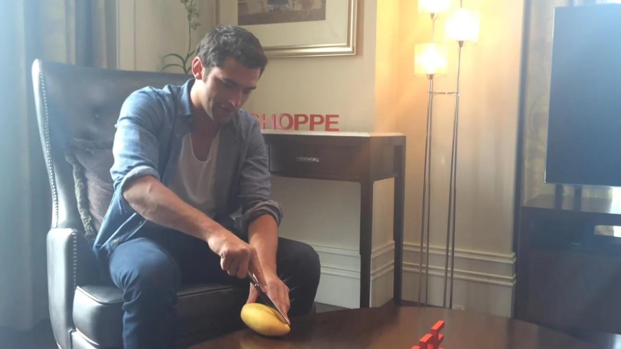 A still from the viral video in which a man attempts to slice a mango in a staged living room setting, which became the basis for the 'Can I Get Another Mango' meme.