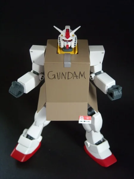 A Gundam figurine customized with a miniature cardboard box, recreating the meme in toy form.