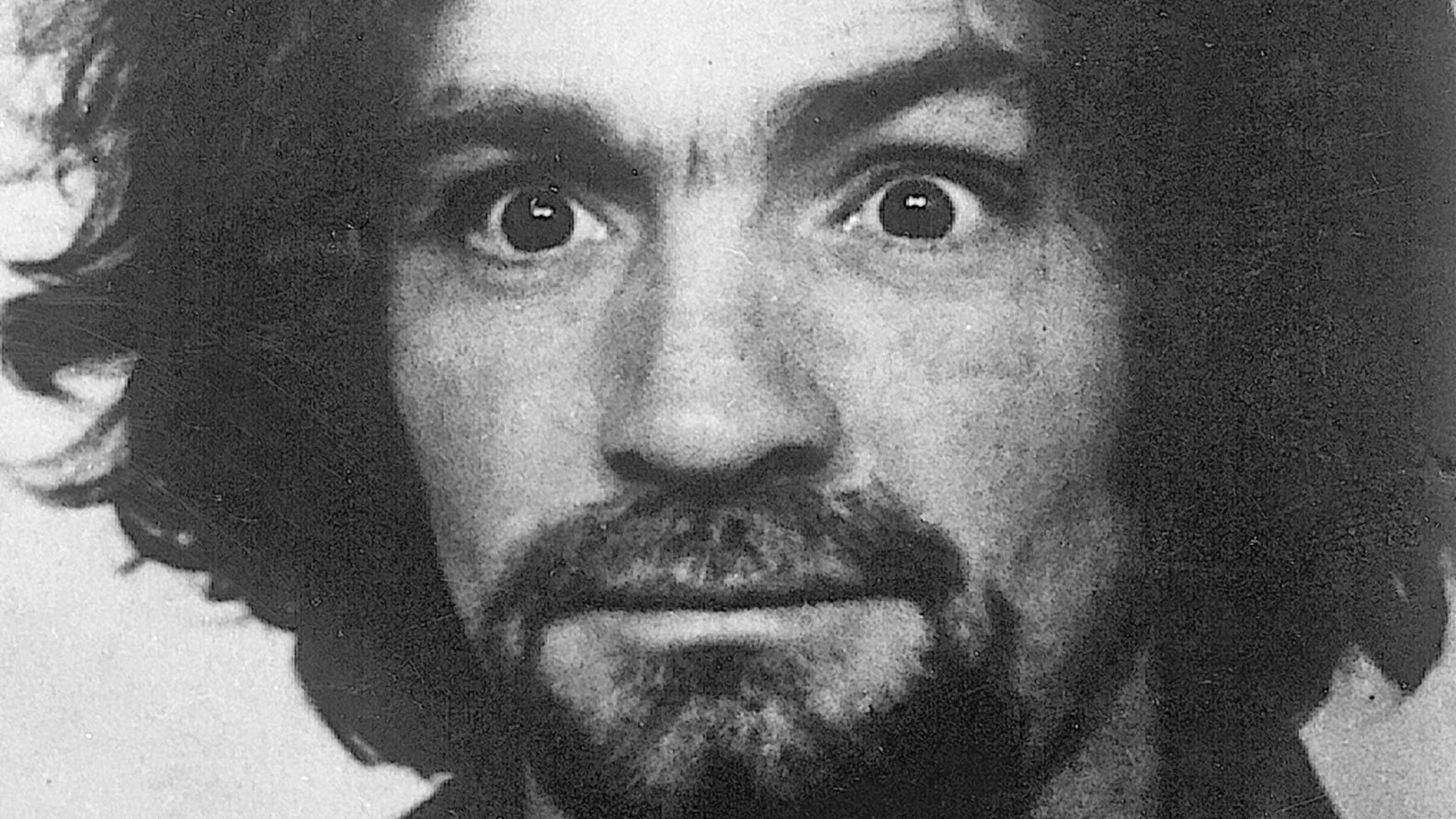 An iconic black-and-white portrait of Charles Manson, whose disheveled appearance and intense stare became a widely referenced image online.