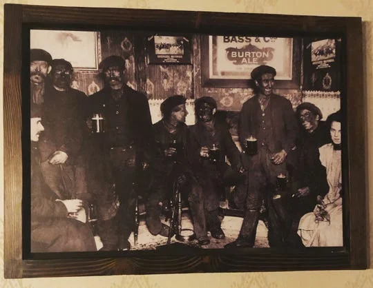 The full framed photograph as published by AZCentral, depicting coal miners with soot-covered faces in a period pub scene.