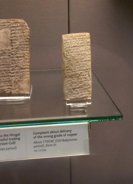 A close-up view of the complaint tablet to Ea-nasir on display, highlighting the museum's explanatory placard.