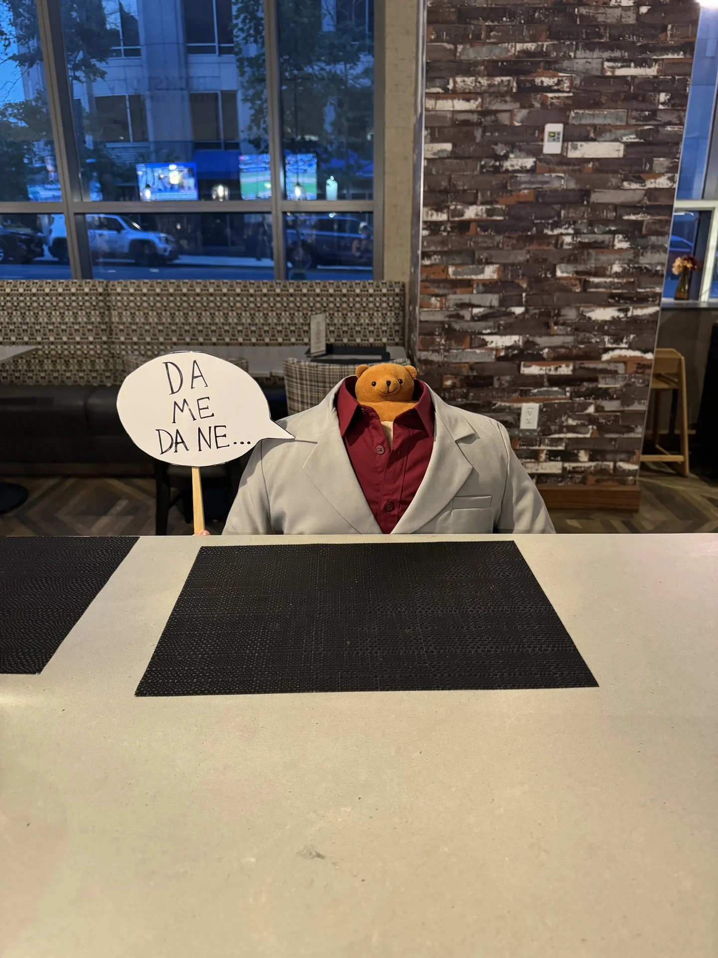 A fan cosplay recreating Kiryu's Dame Da Ne scene using a teddy bear as the head and a handwritten speech bubble.