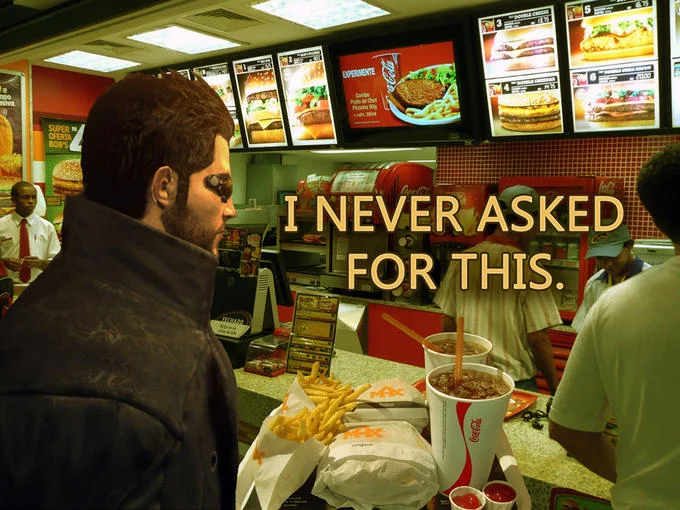 The signature "I never asked for this" meme, edited to place Adam Jensen at a fast food counter — one of the most recognizable Deus Ex jokes online.