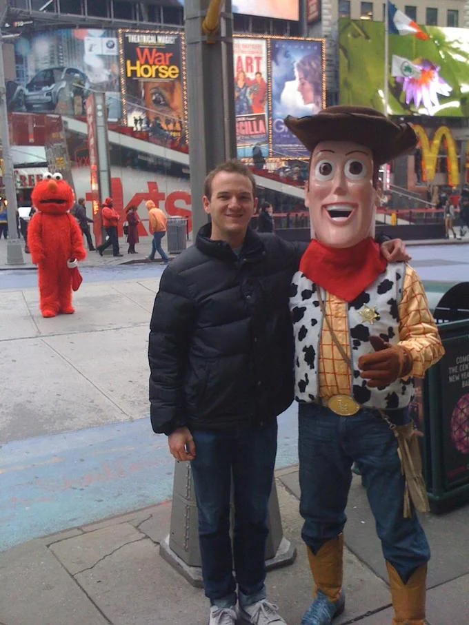 The original Times Square photograph that spawned the Devastated Elmo meme, showing Elmo appearing dejected while the tourist chose to pose with Woody instead.