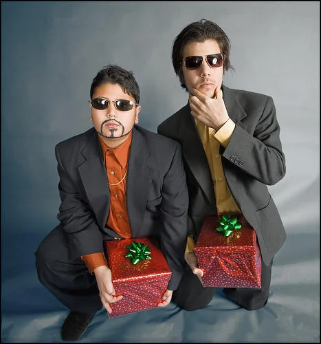 A studio-style cosplay recreation of the 'Dick in a Box' duo with the signature suits, sunglasses, and gift-wrapped boxes.