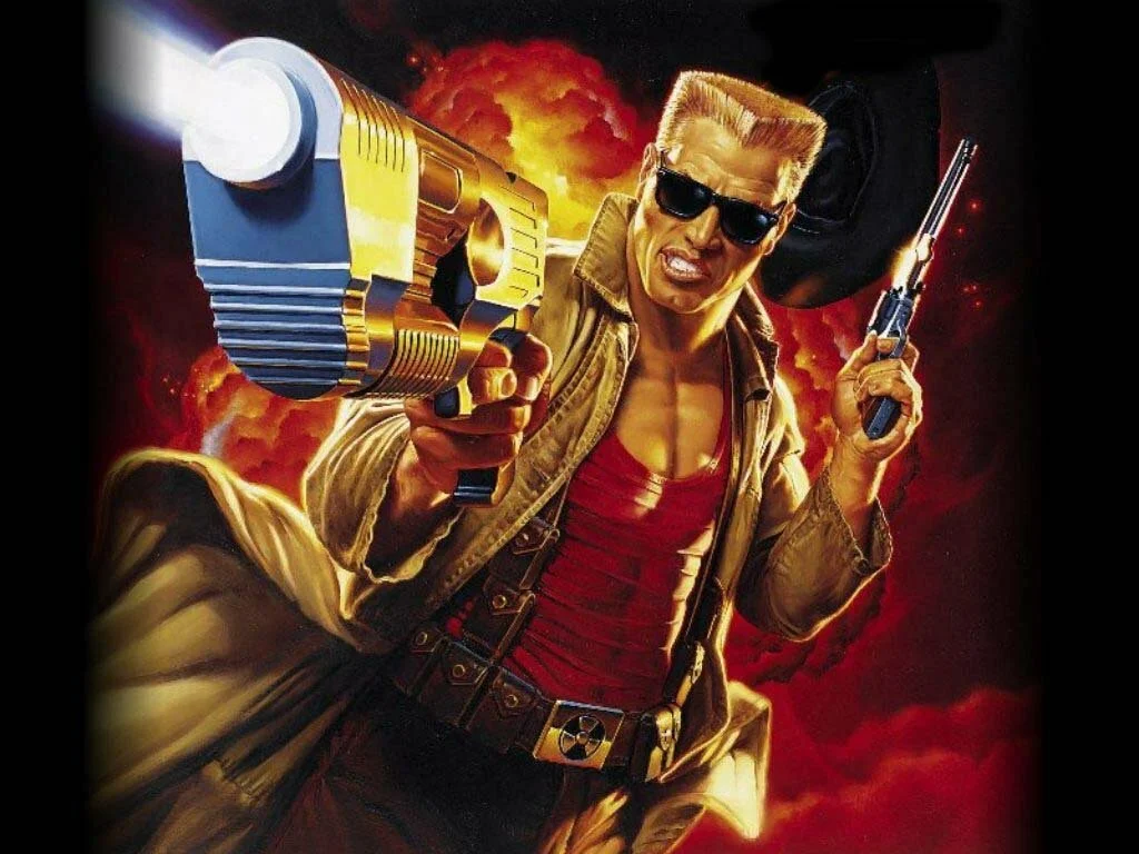 The iconic Duke Nukem promotional artwork, featuring the character's signature flat-top haircut, sunglasses, and dual-wielded weaponry.