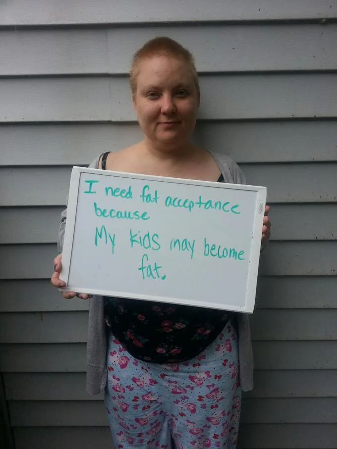 A participant in the 'I Need Fat Acceptance Because' photo campaign holds a whiteboard sign about protecting future generations from body shaming.