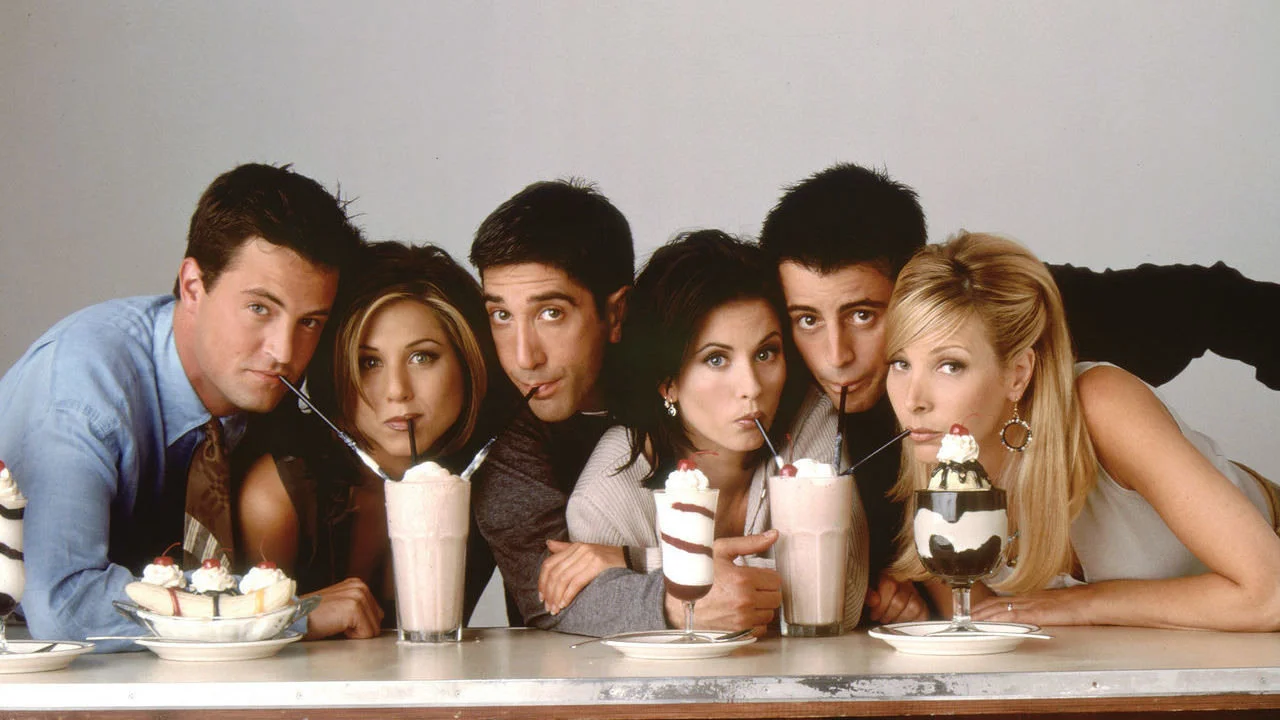 The classic Friends promotional photo featuring the six main cast members sharing milkshakes and sundaes.