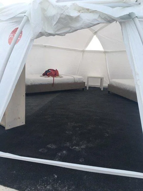 The sparse, water-logged interior of a Fyre Festival tent, far from the luxury accommodations promised in marketing.