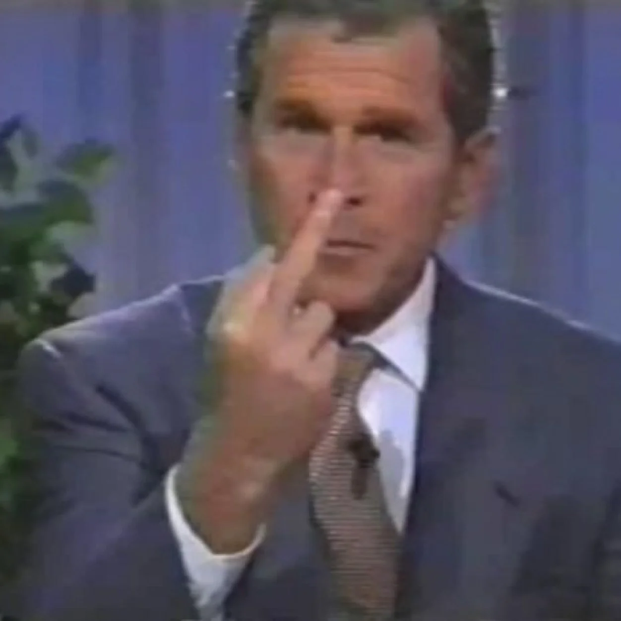 George W. Bush flashes his infamous 'one-finger victory salute' during a televised interview, the moment that became the basis for the meme.