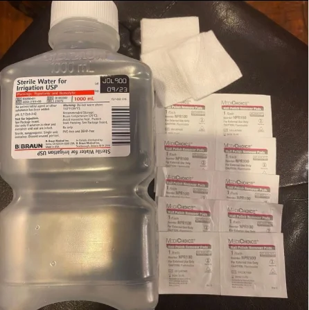 Medical supplies including sterile water and adhesive remover packets from the emergency room visit.