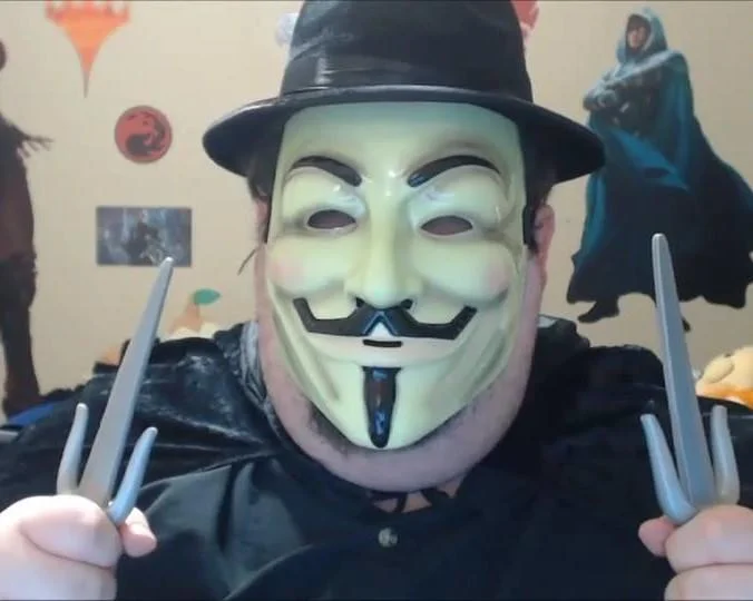 A costumed enthusiast combining the Guy Fawkes mask with a fedora and Wolverine claws — an example of the mask's crossover into pop-culture cosplay.