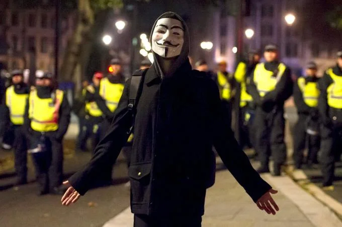 A lone masked protester confronts a police line during the annual Million Mask March.