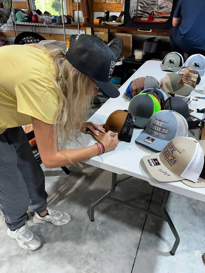 Hailey Welch autographs Hawk Tuah trucker caps ahead of the official merch release.