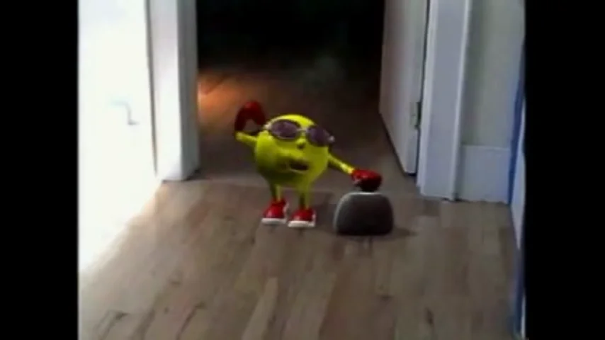 The original viral video screencap that spawned the 'Here Comes Pac-Man' meme, showing the animated Pac-Man toy walking down a hallway.