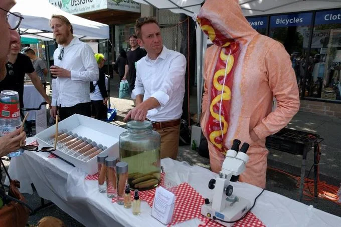 The Hot Dog Water pop-up booth at Vancouver's Car-Free Day 2018, complete with a hot dog mascot costume and pseudo-scientific product display.