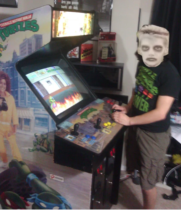 A crossover fan cosplay pairs the 'I like turtles' zombie boy with the Teenage Mutant Ninja Turtles arcade cabinet.
