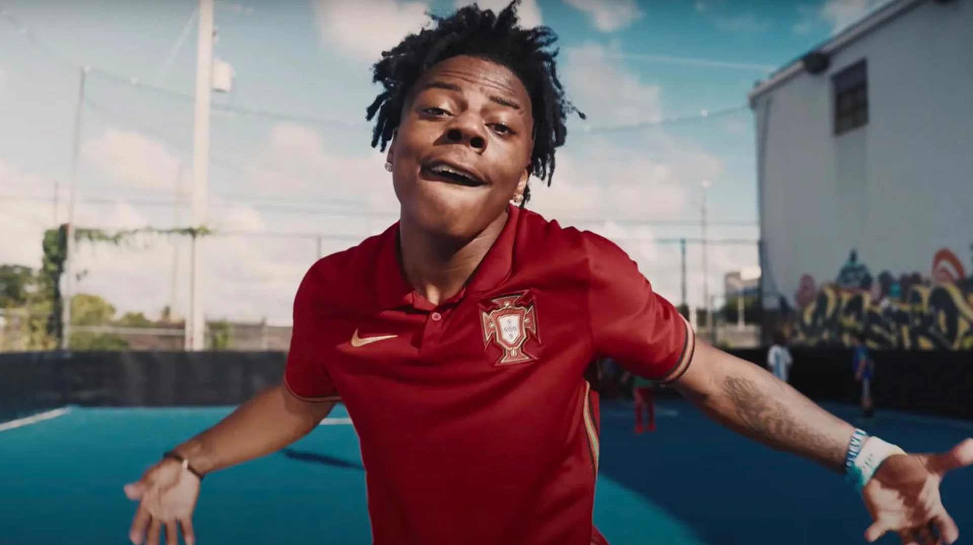 A still from IShowSpeed's 'World Cup' music video, with the streamer wearing a Portugal jersey and posing on an outdoor football pitch.