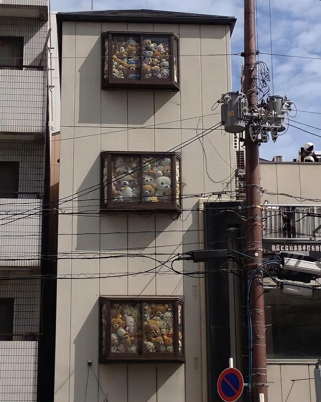A quirky Japanese building with windows crammed full of stuffed animals, an example of the offbeat urban scenes popular in 'weird Japan' meme culture.