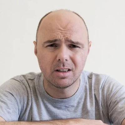 Karl Pilkington, the English television personality known for his deadpan demeanour and round bald head.