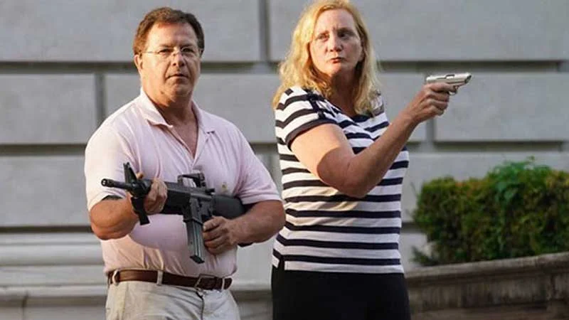 The viral June 2020 photograph of Mark and Patricia McCloskey brandishing firearms at Black Lives Matter protesters outside their St. Louis home.