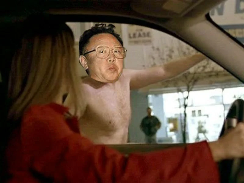 A photoshopped meme variant placing Kim Jong-il's face onto a shirtless figure leaning into a car window, a humorous remix of the 'looking at things' motif.
