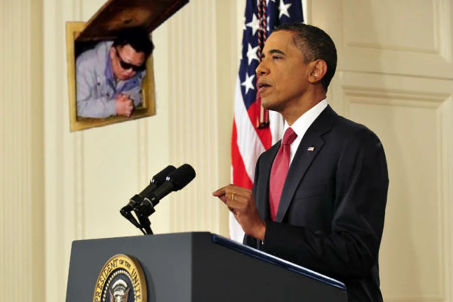 A photoshopped mashup inserting the 'Kim Jong-il in a wall hatch' cutout behind President Obama during a White House address.