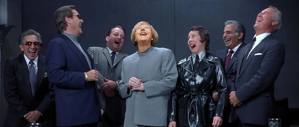 A Photoshop edit places Theresa May's laughing face into an ensemble laughing scene.