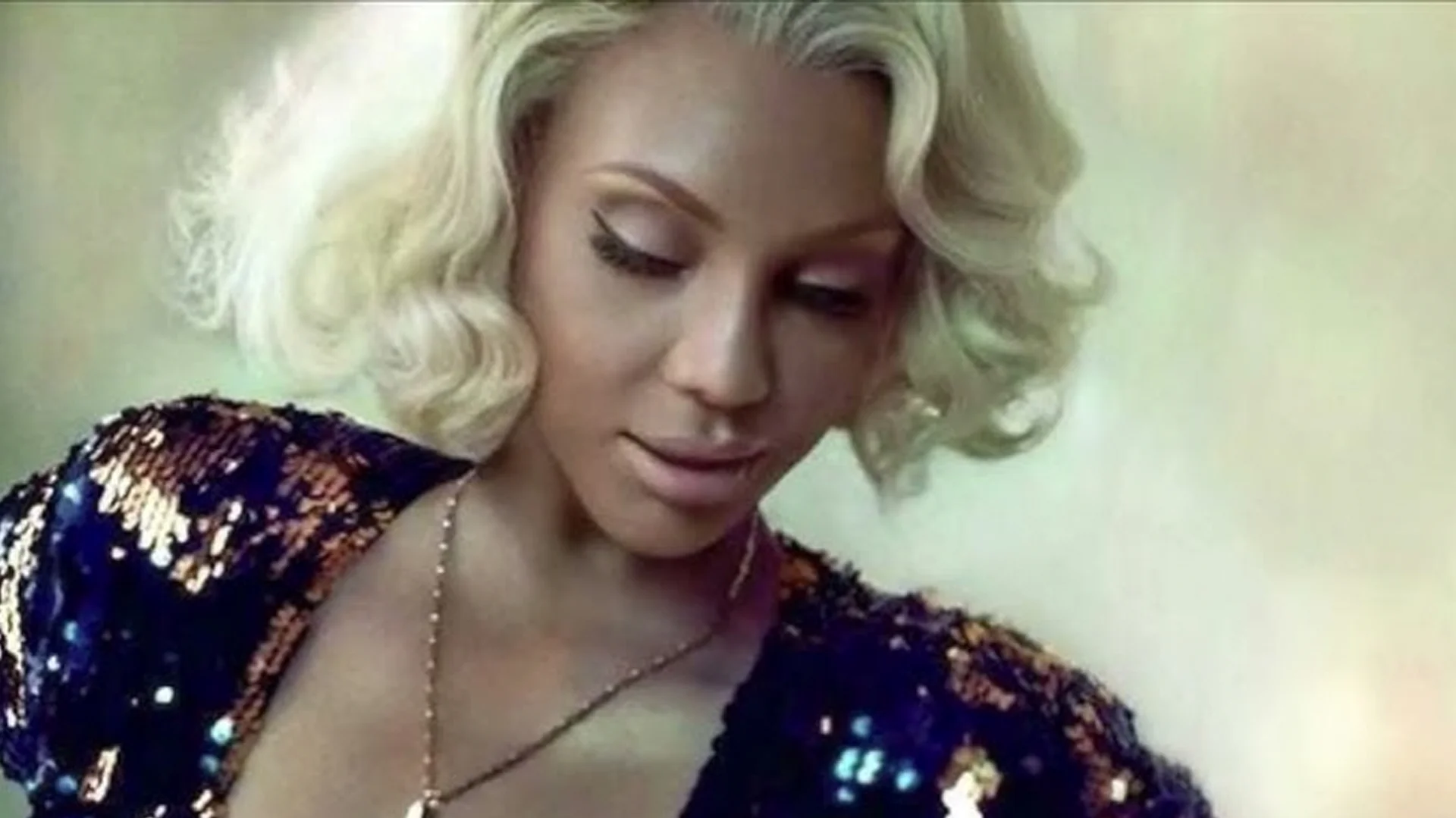 A still associated with the 'Let Me Know, Let Me Know' meme, featuring a blonde-haired woman in a sequined outfit.