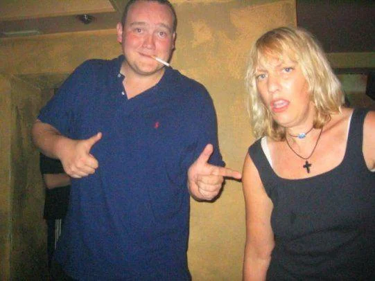 A partygoer performs the Lynndie England pose next to an intoxicated woman at a nightclub, a common subject of the meme.