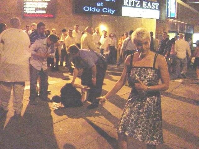 The Lynndie England pose performed next to a passed-out woman on a street, one of the meme's classic urban night-out subjects.