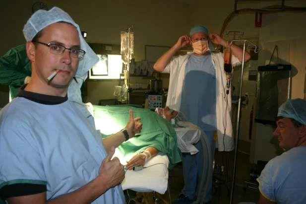 Medical staff enact the Lynndie England pose over an unconscious surgical patient, an early example of the meme spreading beyond the military context.