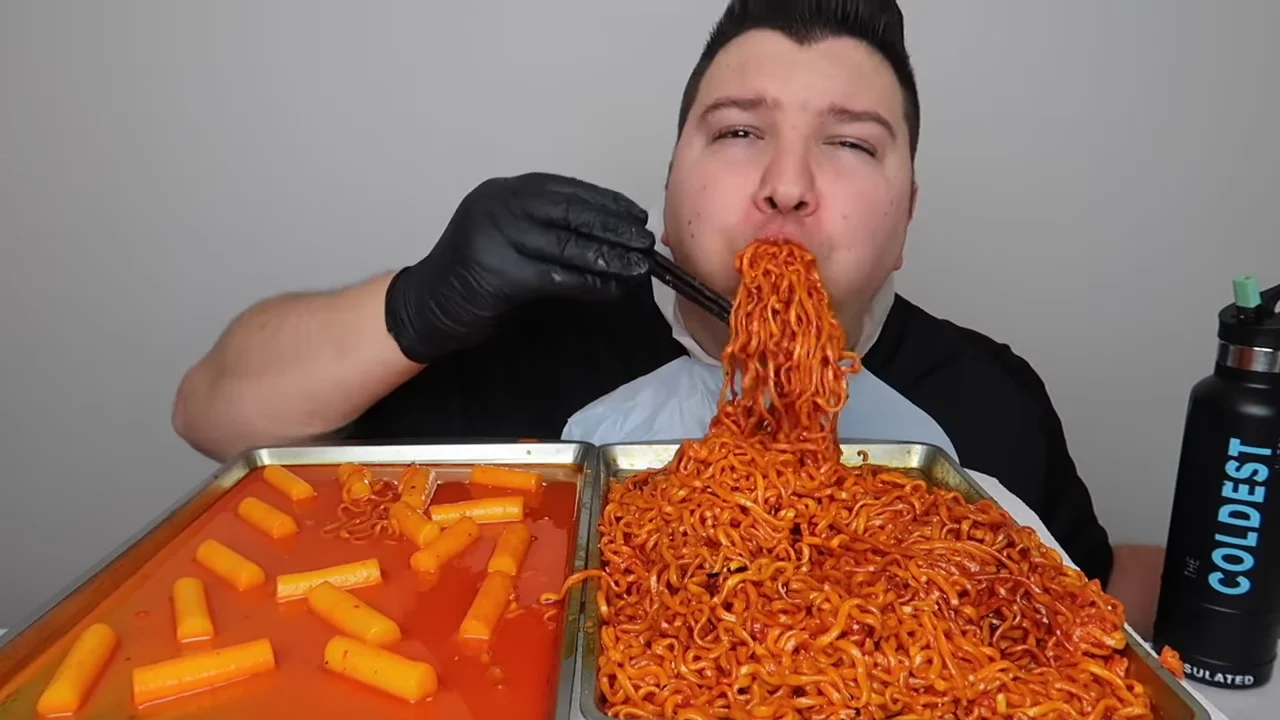 Nikocado Avocado eating noodles in iconic mukbang style.