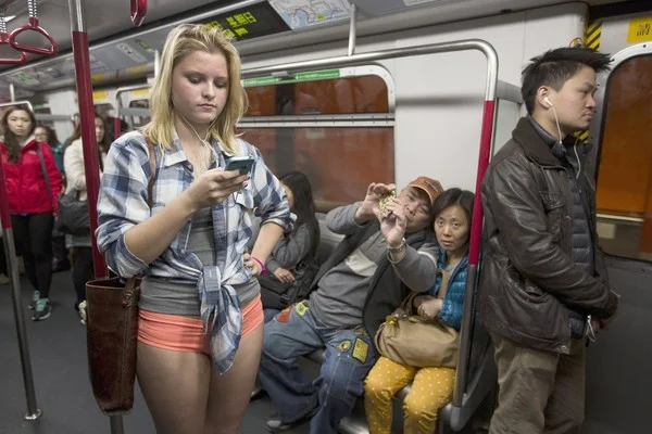 A participant scrolls through her phone during the No Pants Subway Ride, blending in with fellow riders around the world.