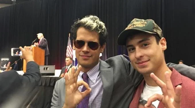 Two men making ok hand gestures at event.
