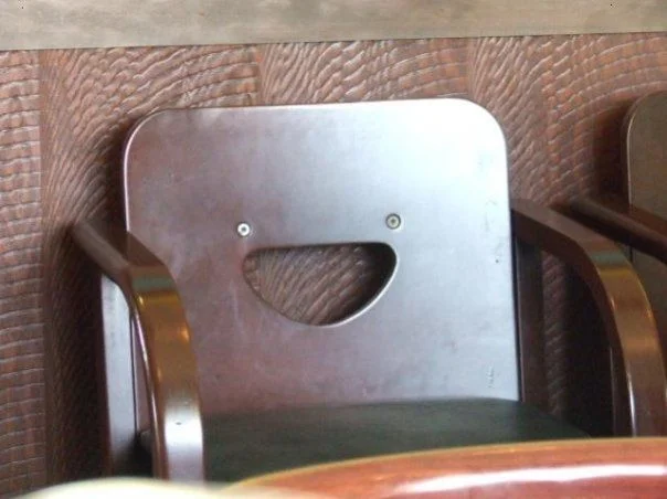 A wooden chair whose backrest cutout and screws form an unmistakable smiling face — a classic example of pareidolia.
