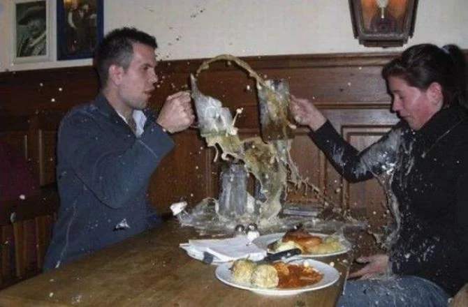 A perfectly timed shot freezes the exact instant a drink erupts across a restaurant table.