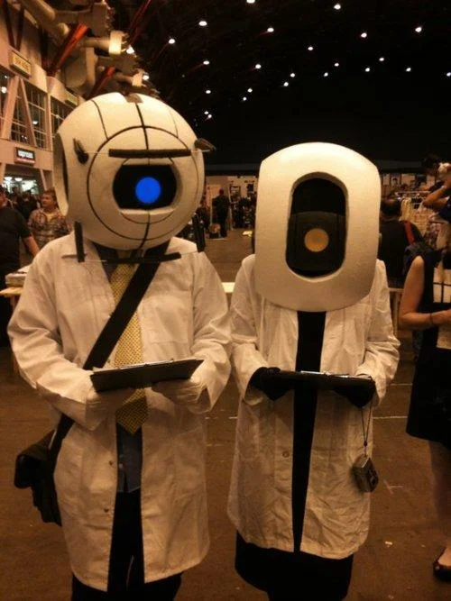 Cosplayers in creative interpretations of the Portal 2 personality cores as Aperture Science scientists.