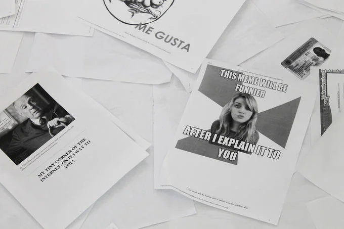 Printed sheets from the exhibit reveal internet memes and image macros submitted by contributors around the world.