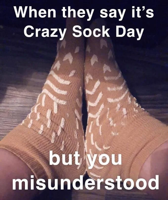 A caption meme joking about mistakenly wearing psych ward grippy socks to a Crazy Sock Day event.