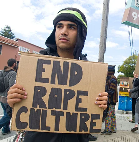 A demonstrator holds an 'End Rape Culture' sign at a street protest, an image often used to represent the movement against rape culture.